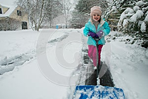 A young girl shoveling snow in a winter storm