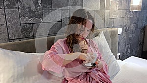 A young girl after a shower in the evening dries her hair sits on a bed in a hotel plays on a mobile phone uses the