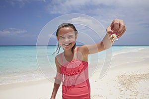 Young girl showing a crab shes collected on the beach