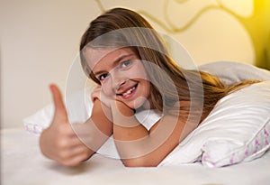 Young girl showing thumbs up sign with a grin, shallow depth photo