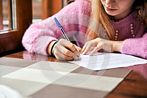 Young girl signs a document. student learns to write an abstract