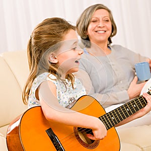 Young girl sing play guitar to grandmother