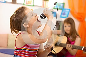 Young girl singing with microphone at home photo