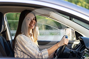 Young girl sit at driver seat in new car smiling hold hands on wheel happy to get driver license