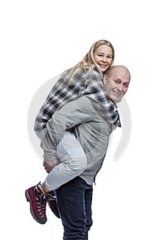 A young girl sits on the back of a bald man. Cute laughing blonde girl in a black and white checkered shirt and jeans and a guy in