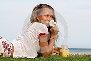 The young girl sits on a grass in the tropical country of the island Samui, the Girl drinks smoothie.