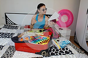 Young Girl sits near suitcase. Girl beside overfilled suitcase. Getting ready for travelling