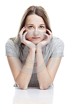 A young girl sits propping her face with her hands.  on a white background. Vertical. Close-up