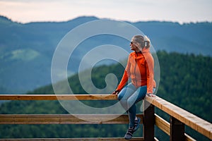 a young girl sits on a wooden handrail.