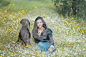 Young girl sittin in flower field together with German Pointer