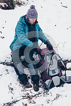 Young girl sitting with backpack in the winter forest