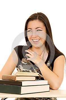 Young girl sitting behind a pile of books laughing