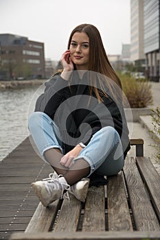 Young girl sitting on the bench in city