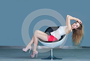 Young girl sitting on chair and touching her hair