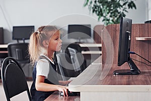 Young girl sitting by the computed and searching for information