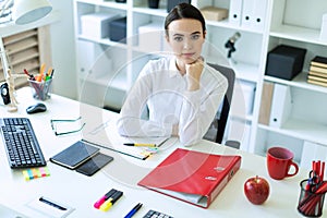 A young girl is sitting at the computer desk in the office.