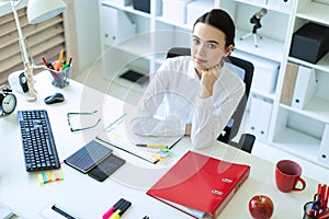 A young girl is sitting at the computer desk in the office.