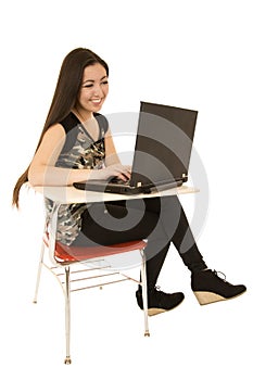 Young girl sitting at desk using computer smiling