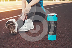 Young girl sitting down with protein shake or water bottle on street after running exercise running workout street