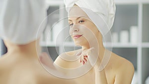 Young Girl is Sitting in front of a Make-up Mirror in the Bathroom and Applying a Skin Cream. Beautiful Woman is Making