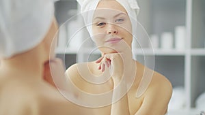 Young Girl is Sitting in front of a Make-up Mirror in the Bathroom and Applying a Skin Cream. Beautiful Woman is Making