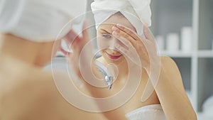 Young Girl is Sitting in front of a Make-up Mirror in the Bathroom and Applying a Skin Cream. Beautiful Woman is Making