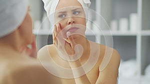 Young Girl is Sitting in front of a Make-up Mirror in the Bathroom and Applying a Skin Cream. Beautiful Woman is Making