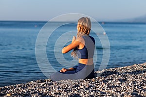 Young girl sitting in Lotus pose on the beach at sunset