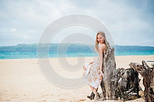 Young girl sitting on an old tree on the beach of Boracay