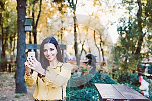 Young girl sitting in the park with the phone in her hands