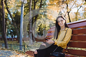 Young girl sitting in the park with the phone in her hands