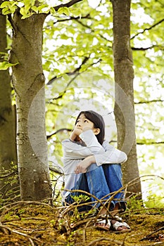 Young girl sitting quietly in woods
