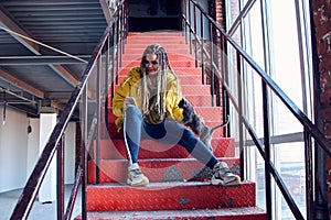 Young girl is sitting on the red stairs. cocky teen millennial