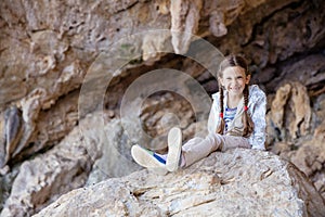 Young girl sitting on rock in climbing sector and smiling