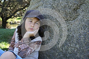 Young girl sitting by rock in park