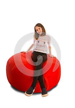 Young girl sitting on round shape red beanbag chair
