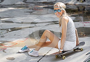 Young girl sitting on skateboard in skatepark
