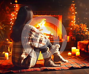 Young girl sitting in sweater and woolen socks by a fireplace.