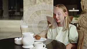 A Young Girl Is Sitting At A Table With Cups Of Coffee
