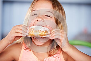 Young Girl Sitting At Table Eating Sugary Donut