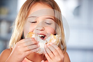 Young Girl Sitting At Table Eating Sugary Donut photo