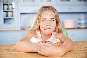Young Girl Sitting At Table Looking At Plate Of Sugary Cakes photo