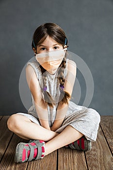 Young girl sitting wearing a protective mask