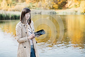 A young girl sketching near a lake in the autumn forest.