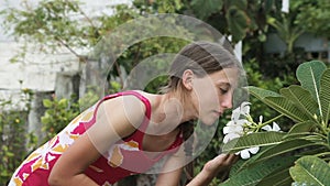 Young girl smelling flower on branch