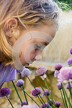 Young girl smelling purple flowers.