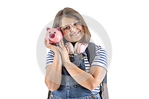 Young girl smiles as she holds her head close to a pink piggybank with savings