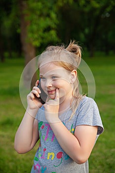 A young girl smiles with her phone in a park in nature