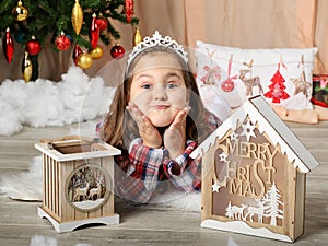 Young girl smililng in front of christmas tree with decorations boxes