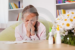 Young girl sneezing at home with paper towel prepared to blow he